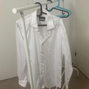 Vit skjorta från Dressmann - Säljer en stilren vit skjorta från Dressmann i slim fit. Skjortan är långärmad och gjord av bomull med stretch för extra komfort. Perfekt för både vardag och fest!