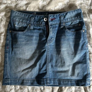 Jeanskjol från Bondelid - Säljer en snygg trendig jeanskjol från Bondelid. Den är i klassisk blå denim med en knapp och dragkedja framtill. Kjolen har fickor både fram och bak, vilket är superpraktiskt. Perfekt för en casual look! Sparsamt använd!! 