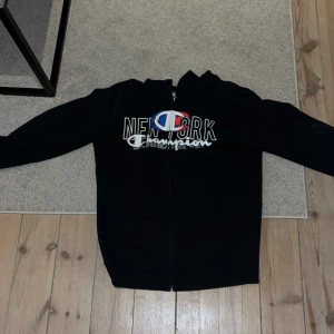 Champion zip up - En svart champion zip up hoodie, ganska tunn. Inga tecken på slitage eller användning förutom att snöret i luvan har åkt ur - se bild 4 och 5