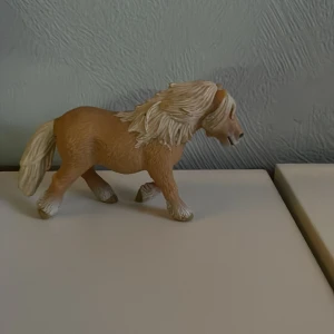 Schleich häst - Säljer en detaljerad brun hästfigur med ljus man och svans. Perfekt för samlare eller som leksak. Figuren har en realistisk design och står stadigt på fyra ben.