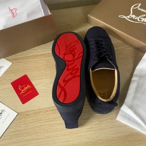 Svarta sneakers från Christian Louboutin - Snygga svarta sneakers från Christian Louboutin med den ikoniska röda sulan. Skorna har en stilren design med snörning och är tillverkade i mocka. Perfekta för den som vill ha en touch av lyx i vardagen.