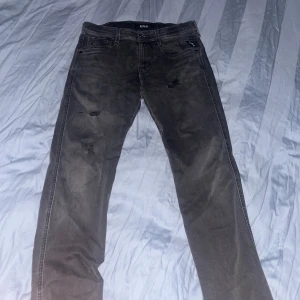 Grå jeans från Replay - Snygga svart/gråa jeans från Replay med slitna detaljer. De har en klassisk femficksdesign och knappgylf. Perfekta för en avslappnad stil. Köpta för 1800 i butik finns kvitto