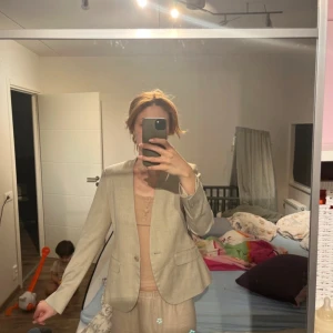 Beige kavaj - Snygg beige kavaj med klassisk design. Perfekt för en stilren look. Kavajen har en enkel knäppning framtill och fickor på sidorna. Passar bra till både vardag och mer formella tillfällen.