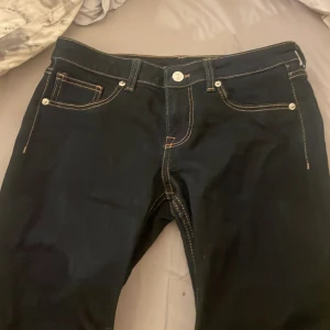 Svarta bootcut jeans - Snygga mörk blåa bootcut jeans med klassisk femficksdesign och kontrasterande sömmar. Perfekta för en stilren look.