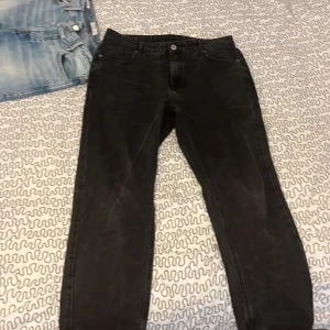 Svarta jeansbyxor - Snygga svarta jeansbyxor med klassisk femficksdesign. De har en knapp och dragkedja framtill. Perfekta för en stilren look.