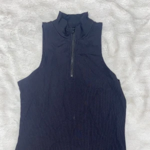 Svart ärmlös klänning från Bik Bok - Snygg svart ärmlös klänning från Bik Bok i ribbat material. Klänningen har en dragkedja framtill och en tight passform som framhäver figuren. Perfekt för en kväll ute eller en speciell tillställning. Dragkedjan öppnas inte den e bah där för å va fin