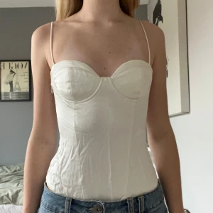 Vit body med smala axelband - Fin vit body som är lite korsett liknande med smala axelband.