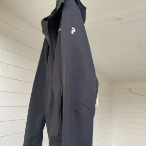 Svart vindjacka från Peak Performance - Säljer en stilren svart jacka från Peak Performance. Jackan har dragkedja framtill och en diskret logga på bröstet. 