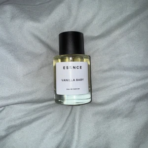 Vanilla Baby Eau de Parfum från Essence - Säljer en flaska Vanilla Baby Eau de Parfum från Essence. Parfymen kommer i en stilren, genomskinlig glasflaska med en svart kork. Doften är söt och vaniljig, perfekt för dig som älskar varma och mjuka toner. Flaskan är enkel och elegant, vilket gör den till ett snyggt tillskott på parfymhyllan. Bara använt pytte lite, max 5 sprejar. Fick en annan parfym i present så behövs inte längre.