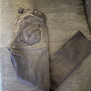 Svarta Dondup jeans  - Snygga svarta jeansbyxor från Dondup med en klassisk femficksdesign. Byxorna har en knappgylf och är tillverkade i ett slitstarkt material. Perfekta för en avslappnad stil. Den har 3 hål i sig.