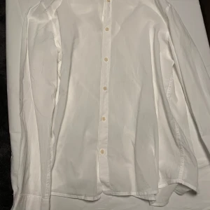 Vit långärmad skjorta från Zara - Klassisk vit skjorta med långa ärmar och knappar framtill. Perfekt för en stilren look. Skjortan har en enkel design som passar till många tillfällen. Storlek M.