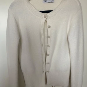 Vit kofta från Zara med pärlknappar - Elegant vit kofta från Zara med unika pärlknappar som ger en lyxig touch. Perfekt för att lägga till en stilren detalj till din outfit. Använd ett fåtal gånger! Jätte mysigt material. Säljer för jag knappt använt.🤍