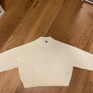 Vit ribbad tröja från H&M Divided - Säljer en stilren vit ribbad tröja från H&M Divided. Tröjan har en croppad passform och långa ärmar. Den är tillverkad i ett mjukt material som ger en bekväm känsla. Passar utmärkt till både jeans och kjol. Den är också rätt tunn vilket leder till att man kan använda den under varmare tider också.