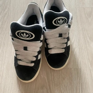 Svarta sneakers från Adidas - Snygga svarta sneakers från Adidas med vita detaljer och snörning. Använd fåtal gånger, lite skitiga men inget fel på dom