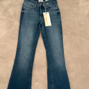 Blå jeans från ONLY - MIDJEMÅTT: 32cm tvärsöver INNERBENSLÄNGD: 74cm Snygga blå jeans från ONLY i modellen ONLBLUSH MID FLARED. De har en klassisk femficksdesign och en lätt utsvängd bootcut-stil. Perfekta för en avslappnad look med en modern twist.