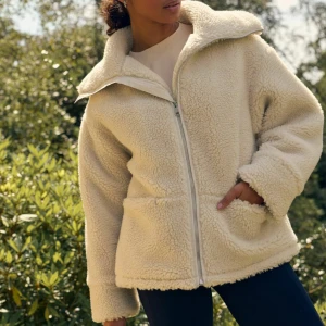 Beige teddyjacka från Next - Mysig beige teddyjacka från Next med dragkedja framtill och två fickor. Perfekt för kyliga dagar med sin fluffiga och varma design. Jackan är helt ny, med lappen kvar. Säljer för 900, nypris 1300kr 