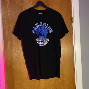 Svart t-shirt från Jack & Jones - Säljer en svart t-shirt från Jack & Jones med trycket 'Paradise Long Beach' i blått och vitt. Perfekt för en avslappnad stil.