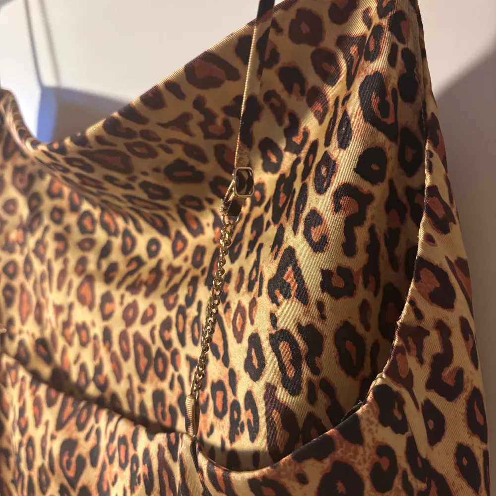 Trendig leopardmönstrad linne i satin med smala axelband som dessutom har en fin guldkedjadetalj och som är justerbara. Inga tecken på användning och passar en S-M. Yläosat.