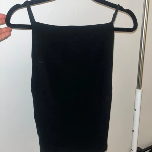 Svart axelbandslös topp - Elegant svart axelbandslös topp med en tight passform. Perfekt för en stilren look. Toppen har en enkel design med smala axelband och en rak skärning. Storlek L men funkar för de flesta då det går att justera banden i ryggen jag har storlek xs-s i toppar och den passar perfekt 