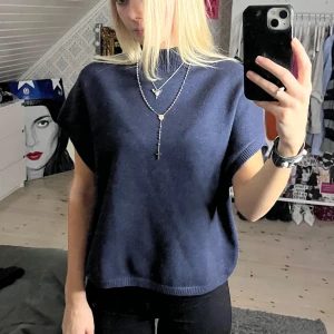 Mörkblå stickad topp - Säljer en snygg mörkblå stickad topp med korta ärmar. Liknar tröjorna ifrån Filippa K. Perfekt för både vardag och fest! Är i bra skick och superbekväm att ha på sig.  