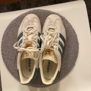 Adidas Gazelle - Fräscha adidas gazelle i strl 40 2/3. Skorna är vita med gröna och guldiga detaljer. Knappt använda!