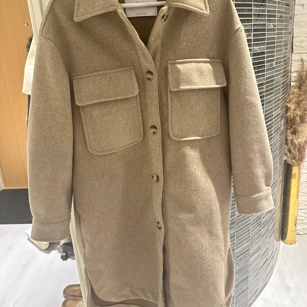 Säljer en snygg beige overshirt från Bershka i mycket bra skick. Den har en normal passform med långa ärmar och stora fickor framtill. Perfekt för höst och vår, och kan stylas både upp och ner. Knapparna framtill ger en cool look. Passar perfekt för lager-på-lager-stil! Oversize modell passar bra s/m/l storlek. Jackor.