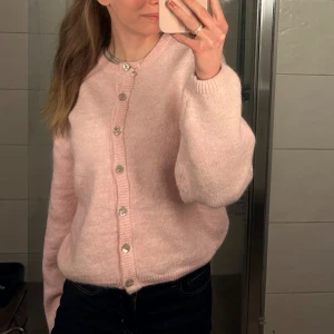 Rosa kofta med knappar - Mysig rosa kofta med glittriga knappar. Perfekt för kyliga dagar och ger en söt touch till din outfit. Långärmad och i en mjuk, stickad kvalitet. 💕💕 Storlek Xs ifrån gina, använd fåtalet gånger. Nyskick!! 