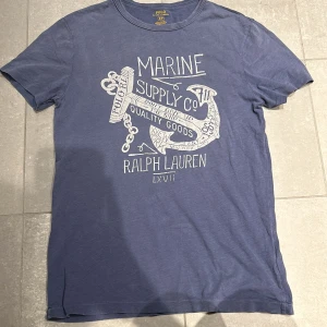 Ralph Lauren T-shirt - Tja! Säljer denna Ralph Lauren tshirten med ett sjysst tryck fram. Den är lite ljus marinblå färg och passar S. Hör av vid frågor!