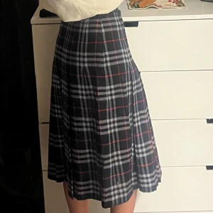 Vintage burberry - Snygg rutig kjol från Burberry i mörkblått med röda och vita rutor. Kjolen har en klassisk design och är perfekt för en stilren look. Den är knälång och har en bekväm passform. Tillverkad i England med 100% ull.💕i otroligt fint skick