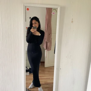 Svart långklänning - Säljer en elegant svart långklänning med långärmad design. Perfekt för höst och vinter, den har en tight passform som framhäver figuren. Klänningen är gjord i ett mjukt och bekvämt material, idealisk för både vardag och festliga tillfällen.