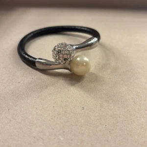 Elegant armband med pärla och strass - Snyggt armband med en stilren design. Det har en svart rem och är dekorerat med en stor vit pärla och en glittrig strassboll i silver. Perfekt för att ge en touch av elegans till vilken outfit som helst. Passar både till vardags och festliga tillfällen. 7 ”pluppar” är av men inget som syns om man inte kollar noga!