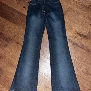 Mörkblå bootcut jeans från SAPA - Snygga mörkblå bootcut jeans från SAPA miss COLLECTION. De är stretchiga och bekväma med hög midja och klassisk femficksdesign. Perfekta för både vardag och fest! Tillverkade av 70% bomull för en skön passform.