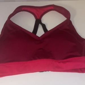 Röd sport-bh från Stadium ny - Säljer en snygg röd sport-bh från Stadium i storlek XS. Den har en bekväm passform med justerbara band och en stabil ryggdesign. Perfekt för träning och ger bra stöd. Använd ett fåtal gånger, så den är i mycket bra skick. Passa på att fynda! 🏋️‍♀️