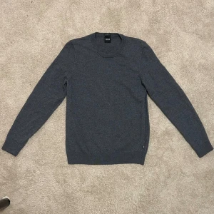Hugo boss tröja - En riktigt fin Hugoboss tröja i Ull. Storlek på den är L men morsan råkade använda lite för varmt vatten när hon tvätta den och nu sitter den som S. Annars super skön och knappt använd