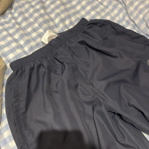 Svarta träningsshorts från Reebok - Säljer ett par mörk blåa träningssbyxor från Reebok. De har en elastisk midja för en bekväm passform och är perfekta för träning. Shortsen är i bra skick och har en diskret Reebok-logga på sidan. storlek xl men passar från S och upp