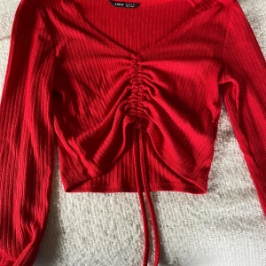 Röd ribbad topp från Shein - Säljer en snygg röd ribbad topp från Shein. Den har långa ärmar och en cool knytning framtill som ger en fin detalj. Perfekt för både vardag och fest!
