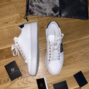 Säljer ett par stilrena vita sneakers från Philipp Plein. De är i storlek 42 och tillverkade i Italien. Perfekta för både vardag och fest! Skorna är av 100% Läder (Nypris:6290kr) Dustbag och alla äkthetsbevis medkommer! 