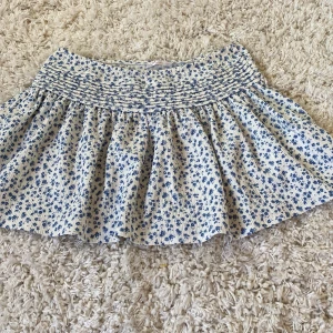 Kjol från Gina tricot i stolek 146 tror jag helt oanvänd  - Helt oanvänd från Gina tricot vit men små blåa gulliga blommor 