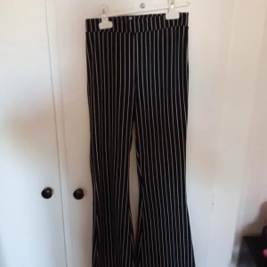 Svart- och vitrandiga byxor från Gina Tricot - Säljer ett par snygga svart- och vitrandiga byxor från Gina Tricot. De är högmidjade och har en rak passform som ger en stilren look. Perfekta för både vardag och fest!