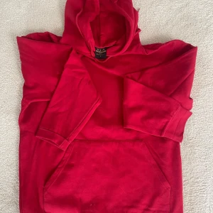 Röd hoodie från Gildan - Säljer en superbekväm röd hoodie. Den är perfekt för kyliga dagar med sin mjuka insida och stora ficka framtill. Den har en klassisk passform och en praktisk huva. Perfekt för både vardag och mysiga hemmakvällar!