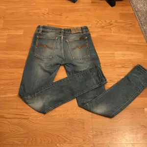 Säljer ett par snygga blå jeans från Nudie Jeans i storlek W28 L32. De är tillverkade av 100% ekologisk bomull och har en klassisk femficksdesign. Skick 8,5/10