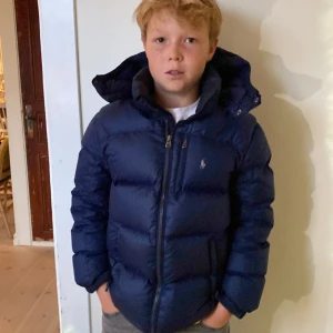 Ralph lauren jacka  - Jackan är i storlek 160- 180 barn L  Skulle säga att jackan passar både tjejer och killar som är i längden 138-152cm ungefär. Jackan är i strålande skick 9/10 och perfekt för de lite kallare årstiderna. Tveka inte på att höra av dig angående frågor. 