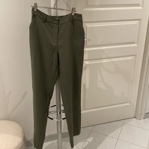 Kostymbyxor  - Kostymbyxor i en grön färg, raka i benen och är medelhög i midjan. Bra skick 