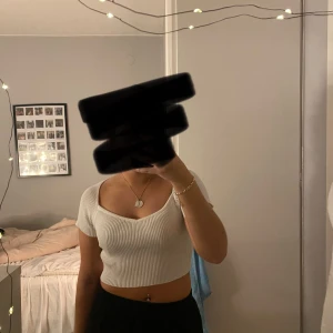 Vit ribbad topp - Säljer en superfin vit ribbad topp med korta ärmar. Den är croppad och har en snygg v-ringad design. Perfekt för både vardag och fest! Använd någon gång