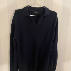 Mörkblå långärmad tröja från Riley - Snygg svart långärmad tröja från Riley med krage. Perfekt för en stilren look. Tröjan har en klassisk design och är tillverkad i ett mjukt material. Tveka inte att hojta till vid eventuella frågor! 