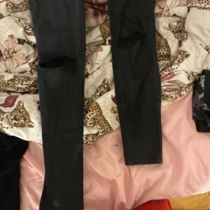 Svarta jeans från NA-KD - Snygga svarta jeans från NA-KD med slitna detaljer på knäna. Perfekta för en trendig look. De har en klassisk femficksdesign och knäppning fram.dom är använda men inte för mycket hade dom under nästan hela förra augusti 😊