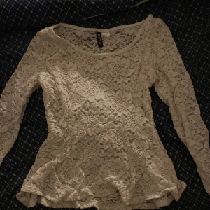 Vit spetsblus från H&M - Säljer en elegant vit spetsblus från H&M med långa ärmar och en rund halsringning. Perfekt för att ge en romantisk touch till din outfit. Blusen har en fin struktur och är lätt att matcha med olika stilar.