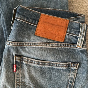 Levi's 511 Jeans - Snygga Levi's 511 jeans i en klassisk blå tvätt. Dessa jeans har en slim passform och är tillverkade i slitstarkt denim. Perfekta för en stilren look med fem fickor och knappgylf.
