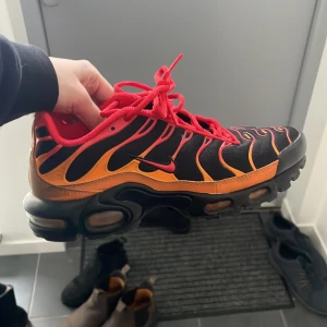 Nike sneakers i svart och orange och röd - Snygga Nike air max med en iögonfallande design i svart och orange. Skorna har röda snören och en robust sula med tydliga mönster för bra grepp. Perfekta!