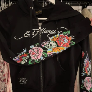 Ed Hardy kofta - Snygg svart croppad kofta från Ed Hardy med färgglatt blommigt tryck och dödskallar på ärmarna och ryggen. Den är i stl S och använd några få gånger 🌸💀